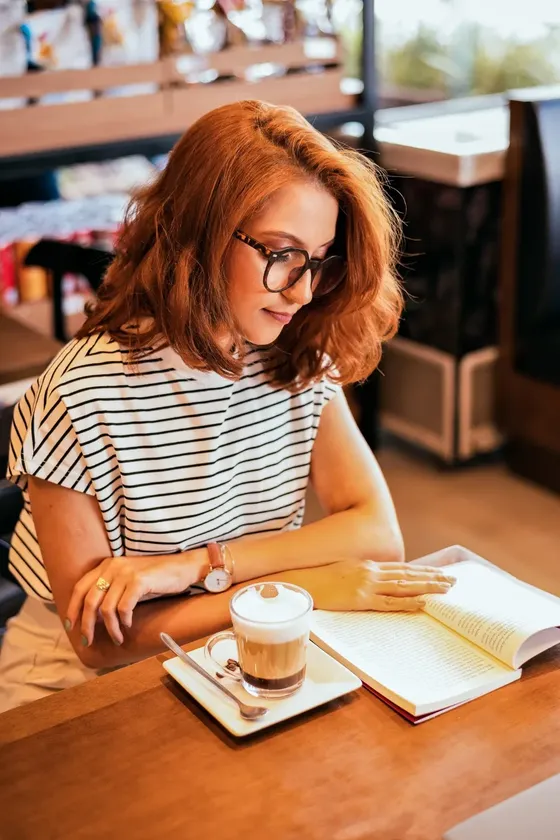 Sabrina Baier lendo um livro com um café